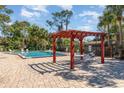 Community pool area with a pergola, chairs, and seating, surrounded by mature trees at 4828 Pebble Beach Dr # A, Orlando, FL 32811