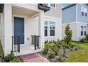 Inviting front porch view with a blue entry door, black railings and brick-laid walkway at 5099 Railroad Vine Aly, Winter Garden, FL 34787