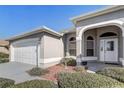 Home featuring an arched entryway and a two-car garage, complemented by low-maintenance landscaping at 7233 Se 171St Pond Ln, The Villages, FL 32162