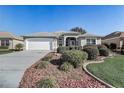 Charming home featuring a well-manicured front yard with beautiful landscaping and an attached two-car garage at 7233 Se 171St Pond Ln, The Villages, FL 32162