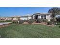 Single-story home boasts manicured lawn, garden beds, and an attached two-car garage at 7233 Se 171St Pond Ln, The Villages, FL 32162
