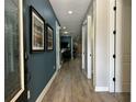 Inviting hallway with wood flooring and decorative wall art leading to other rooms in the house at 7668 Wilmington Loop, Kissimmee, FL 34747