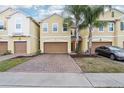 Inviting townhomes feature two-car garages, brick paver driveways, lush landscaping, and mature palm trees at 9819 Red Eagle Dr, Orlando, FL 32825