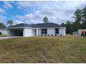 New single-story home featuring a bright white exterior, an open garage, and fresh landscaping at 12929 Sw 82Nd Avenue Rd, Ocala, FL 34473