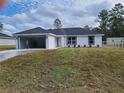 A modern single-story home showcases a white exterior, black roof, and an inviting open garage at 12929 Sw 82Nd Avenue Rd, Ocala, FL 34473