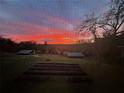 Backyard with a fiery sunset, lush green grass, and two sheds are partially obscured by a screen at 13045 Mountain Trail, Clermont, FL 34715