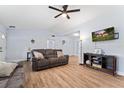 Bright living room with light wood floors, ceiling fan, and a mounted television over a dark wooden console at 1412 Lakecrest Dr, Apopka, FL 32703