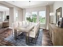 An open-concept dining room with a wooden table, eight upholstered chairs, a modern chandelier, and three large windows at 16420 Silver Grove Blvd, Winter Garden, FL 34787