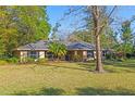 Inviting single-story home featuring a well-maintained lawn, mature trees, and classic architectural details at 33639 Wesley Rd, Eustis, FL 32736