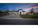 Beautiful single-story home with barrel tile roof, brick paver driveway, and manicured lawn at dusk at 3704 Via Monte Napoleone Dr, Poinciana, FL 34759