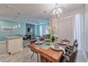 Well-lit dining area with a modern chandelier, a large wood table set, and a view into the living room at 4967 Windermere Ave, Kissimmee, FL 34746