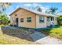 A view of the back side of a ranch style home with a side entry door, simple windows, and a concrete walk way at 866 Gatlin Ave, Orlando, FL 32806