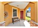 Cozy covered porch featuring a decorative bench and a view of the manicured front yard at 9472 Sw 76Th St, Ocala, FL 34481