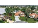 Beautiful aerial shot of a home with a well-manicured yard, driveway, and access to a serene lake at 100 Honeywood Ct, Kissimmee, FL 34743