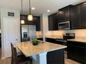 Well-lit kitchen with stainless steel appliances, a granite-topped island with seating, and dark cabinetry at 1013 Flowing Tide Dr, Orlando, FL 32828