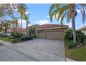 Beautiful home with a well manicured front lawn, red tiled roof, neutral paint color, and brick paved driveway leading to a two car garage at 11733 Delwick Dr, Windermere, FL 34786