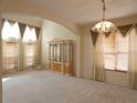 Spacious living room featuring carpeted floors, a decorative cabinet, and large windows with custom curtains at 1230 Elegance Ct, Orlando, FL 32828