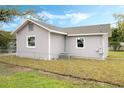 View of a gray home's backyard with a chain fence, window, and partial view of the roof at 230 Hennis Rd, Winter Garden, FL 34787