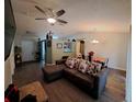 Open-concept living room featuring laminate flooring, ceiling fan, and views into dining and kitchen at 550 Oak Branch Cir, Kissimmee, FL 34758