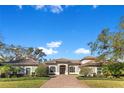 Beautiful one-story home boasts lush landscaping, complemented by a brick driveway under a clear blue sky at 8718 Shimmering Pine Pl, Sanford, FL 32771