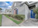 Attractive gray home featuring a blue front door, coordinated shutters and trimmed hedges at 13046 Island Breeze Ct, Orlando, FL 32824