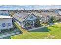 Aerial view of a well-maintained single-story home with solar panels, a front porch, and lush green lawn at 13333 Beebe Aly, Orlando, FL 32827