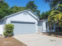 Single-story home featuring a gray two-car garage door, well-kept landscaping, and a concrete driveway at 1346 Rolling River Rd, Deland, FL 32720