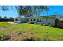 Green backyard features a covered patio, mature trees, and the exterior of the single-story house at 161 Randia Dr, Orlando, FL 32807