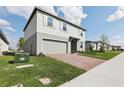 A two-story home with a brick driveway, attached garage, gray siding, and light blue shutters at 2311 White Tail St, Davenport, FL 33837