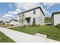 A two-story home with gray siding, light blue shutters, a well-manicured lawn, and a paved sidewalk at 2311 White Tail St, Davenport, FL 33837