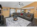 Spacious living room featuring a large gray sectional sofa, ceiling fan and dark wood flooring at 2454 Whitehorse St, Deltona, FL 32738