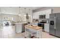 Modern kitchen featuring stainless steel appliances, white cabinets, a kitchen island and open to the living area at 2526 Winsome Way, Davenport, FL 33896