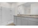 Bathroom featuring a dual-sink vanity with granite countertop and a walk-in shower, offering modern convenience at 2921 Sunridge Loop, St Cloud, FL 34771