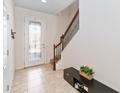 Bright foyer with tile flooring, staircase with wooden banister, and a decorative glass front door at 3566 Southern Cross Loop, Kissimmee, FL 34744