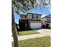 Two-story tan home with a two-car garage and a well-manicured lawn at 3566 Southern Cross Loop, Kissimmee, FL 34744