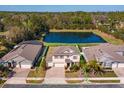 Aerial view of a two-story home with a pond in the background, green lawn, and three-car garage at 5142 Sage Cedar Pl, Sanford, FL 32771