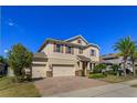 Two-story home with a three-car garage, brick driveway, and well-maintained lawn and landscaping at 5142 Sage Cedar Pl, Sanford, FL 32771