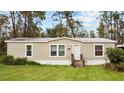 Inviting single-story home with light siding, complemented by a well-maintained lawn and mature trees at 8122 Pine Island Rd, Clermont, FL 34711