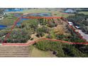 Expansive aerial view of a property with marked boundaries, lush greenery, multiple ponds and cultivated fields at 8122 Pine Island Rd, Clermont, FL 34711