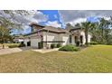 Inviting home featuring a lush green lawn, trimmed bushes, and a stone accent wall at 842 Aldenham Ln, Ormond Beach, FL 32174