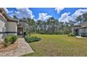 Spacious front yard featuring a well-manicured lawn, lush landscaping, and a brick walkway leading to the front door at 842 Aldenham Ln, Ormond Beach, FL 32174