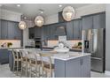 Modern kitchen with gray cabinets, stainless steel appliances, island with seating and three pendant lights at 1593 Evening Summit Cir, Minneola, FL 34715