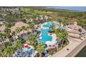 Aerial shot of community pool with beach entry, splash pad, slide, and mature landscaping at 1950 Windward Oaks Ct, Kissimmee, FL 34746
