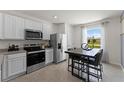 Modern kitchen with white cabinets, stainless steel appliances, gray countertops and tile floors, and an eat-in kitchen table at 3322 Wye Oak Dr, Apopka, FL 32703