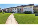 A view of the condo complex exterior with manicured lawn and concrete sidewalk leading to the building at 3800 Saxon Dr # 19B, New Smyrna Beach, FL 32169