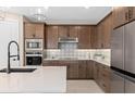 Well-equipped kitchen featuring custom cabinetry, stainless steel appliances, and stylish backsplash at 6920 Dappled Oak Way, Orlando, FL 32829