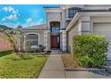 Inviting home entrance with a landscaped walkway leading to a stylish, dark-red front door at 1096 Ballyshannon Pkwy, Orlando, FL 32828