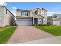 Charming two-story home featuring an attached two-car garage, brick-paved driveway, and manicured lawn at 1171 Lone Palm Way, St Cloud, FL 34771