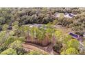 Aerial view of property featuring home, barn, and wooded acreage at 11811 Kijik Trl, Groveland, FL 34736