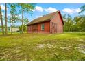 A charming red barn with a brown roof and crossed doors sits on a grassy lawn at 11811 Kijik Trl, Groveland, FL 34736